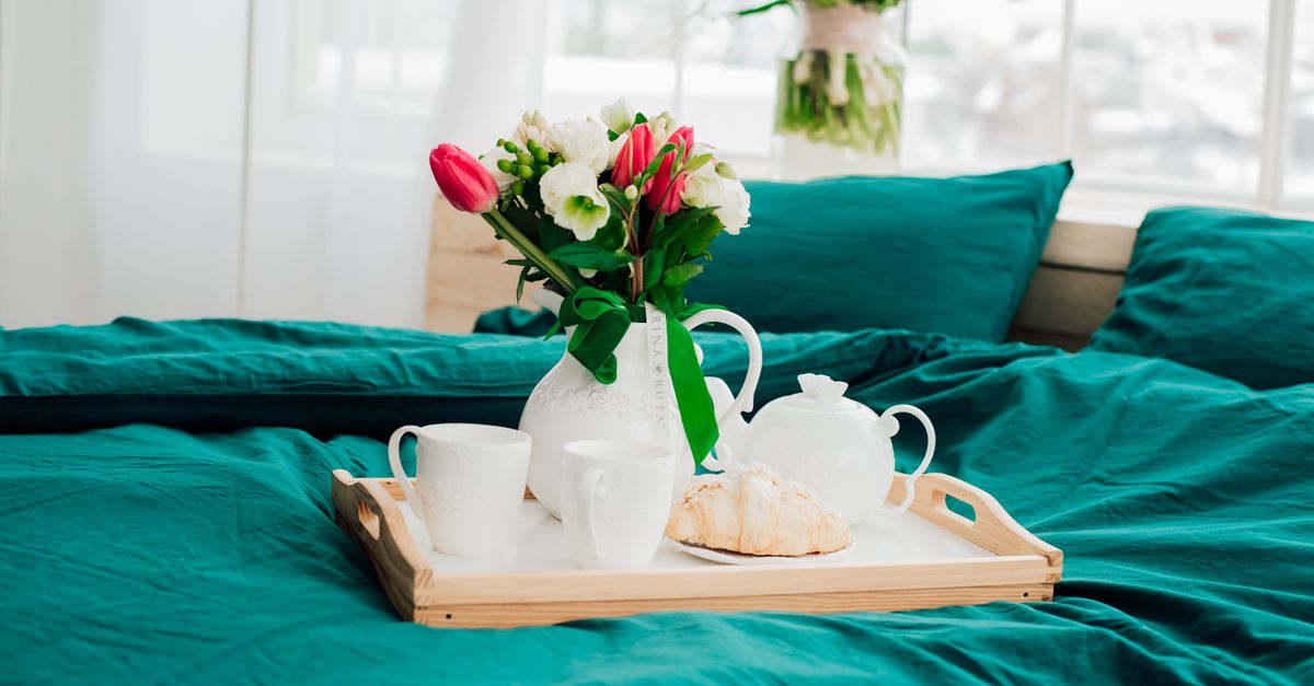 Bright bedroom scene with breakfast tray, flowers, and teal bedding for a peaceful morning vibe.